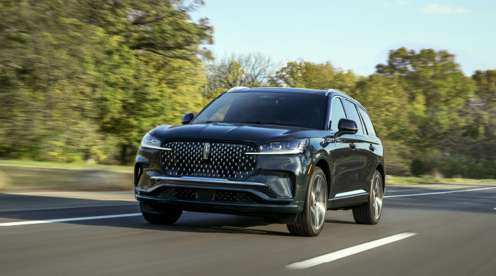 A 2025 Lincoln Black Label Aviator® SUV is being driven down a road lined with trees. | Greenwood Lincoln in Bowling Green KY