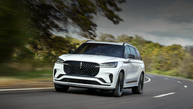 A white 2025 Lincoln Aviator® SUV is being driven down a road lined with trees. | Greenwood Lincoln in Bowling Green KY