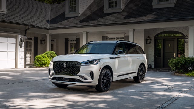 A white 2026 Lincoln Aviator® SUV is parked in the driveway of a luxury home. | Greenwood Lincoln in Bowling Green KY