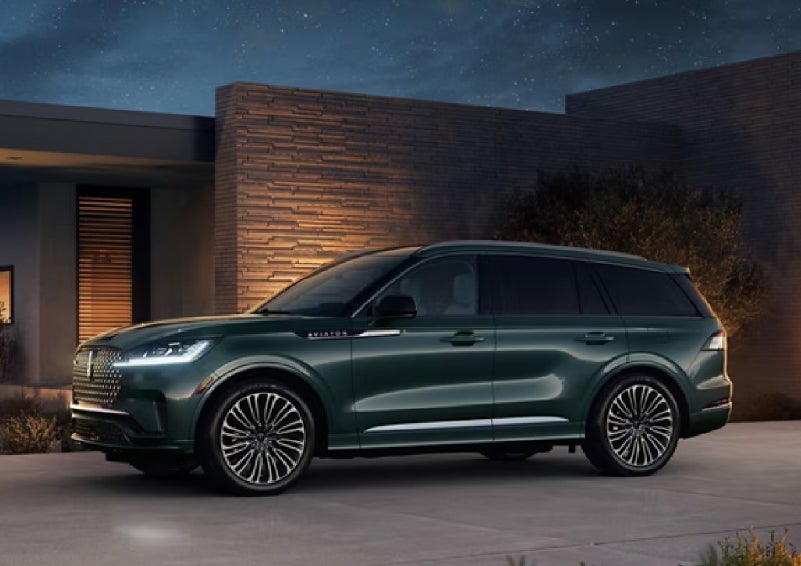 A green 2027 Lincoln Aviator® SUV is parked outside a contemporary home. | Greenwood Lincoln in Bowling Green KY