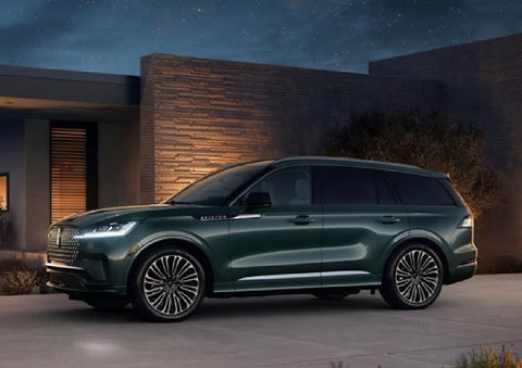 A green 2027 Lincoln Aviator® SUV is parked outside a contemporary home. | Greenwood Lincoln in Bowling Green KY
