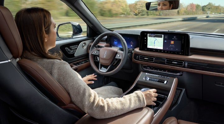 A 2027 Lincoln Aviator® SUV is being driven hands-free on a highway lined with trees. | Greenwood Lincoln in Bowling Green KY