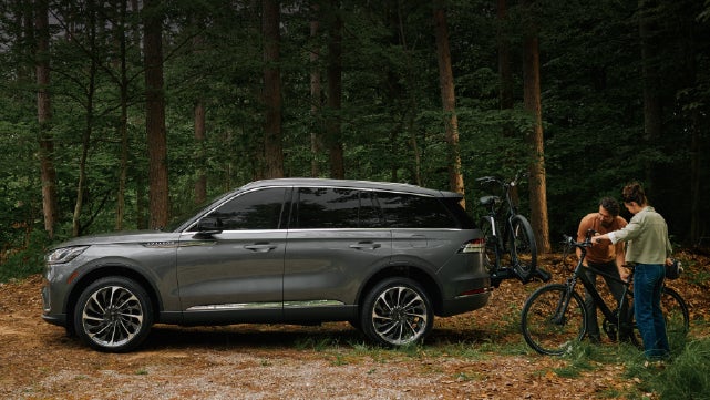 A father and son load e-bikes on a bike rack attached to a 2027 Lincoln Aviator® SUV. | Greenwood Lincoln in Bowling Green KY